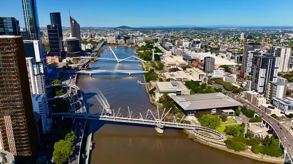 Queensland, Avustralya 'daki Brisbane CBD' nin hava görüntüsü modern silueti, Brisbane Nehri ve çevre kentsel manzarayı gözler önüne seriyor. Yüksek binalar, köprüler ve nehir kenarındaki gelişmelerle fotoğraf, bir tanesinin dinamik enerjisini yakalıyor.