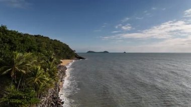 Cairns, Queensland 'daki Trinity Plajı, bu 4K hava aracı görüntülerinde, palmiye ağaçları, Taylor Point burnu, sahil tatil beldeleri ve Mercan Denizi' nin turkuaz sularıyla çevrili manzaralı bir plajı göstermektedir. Görüntüler tropikal bölgeleri gösteriyor.