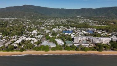 Cairns, Queensland 'daki Trinity Plajı, bu 4K hava aracı görüntülerinde, palmiye ağaçları, Taylor Point burnu, sahil tatil beldeleri ve Mercan Denizi' nin turkuaz sularıyla çevrili manzaralı bir plajı göstermektedir. Görüntüler tropikal bölgeleri gösteriyor.
