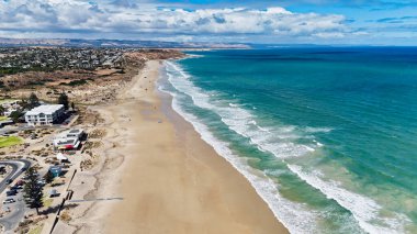 Güney Avustralya 'daki Moana Sahili doğal güzellik ve rahat kıyı yaşam tarzının çarpıcı bir karışımını sunuyor. Bu 4K hava aracı görüntüsü altın kumlu kıyıları, yumuşak sörfleri, engebeli uçurumları ve yerleşim alanlarını görüntüler. Üzerine konulmuş