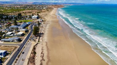 Güney Avustralya 'daki Moana Sahili doğal güzellik ve rahat kıyı yaşam tarzının çarpıcı bir karışımını sunuyor. Bu 4K hava aracı görüntüsü altın kumlu kıyıları, yumuşak sörfleri, engebeli uçurumları ve yerleşim alanlarını görüntüler. Üzerine konulmuş