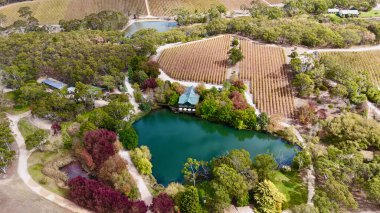 Güney Avustralya, Kuitpo 'da bulunan K1 Şaraphanesi, Adelaide Hills' in güneyinde yer alan ünlü bir şaraphanedir. Bu hava aracı görüntüsü, verimli üzüm bağları ve ormanlık alanlarla çevrili sakin bir göle yansıyan güzel sonbahar renklerini yakalar. Şey...