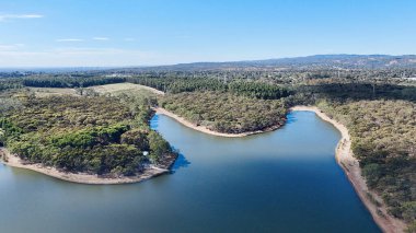 Adelaide, Güney Avustralya 'daki Happy Valley Reservoir Reserve doğayı, suyu ve eğlenceyi birleştiren pitoresk bir manzara sunuyor. Bu hava görüntüsü sarmal kıyı şeritlerini, sık ormanlık alanları ve barajın huzurlu mavi sularını gösteriyor.
