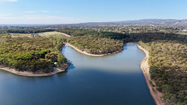 Adelaide, Güney Avustralya 'daki Happy Valley Reservoir Reserve doğayı, suyu ve eğlenceyi birleştiren pitoresk bir manzara sunuyor. Bu hava görüntüsü sarmal kıyı şeritlerini, sık ormanlık alanları ve barajın huzurlu mavi sularını gösteriyor.