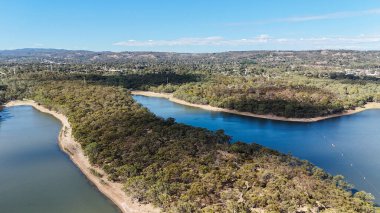 Adelaide, Güney Avustralya 'daki Happy Valley Reservoir Reserve doğayı, suyu ve eğlenceyi birleştiren pitoresk bir manzara sunuyor. Bu hava görüntüsü sarmal kıyı şeritlerini, sık ormanlık alanları ve barajın huzurlu mavi sularını gösteriyor.