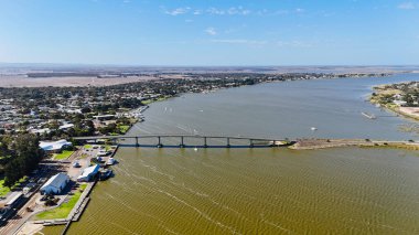 Güney Avustralya 'da Murray Nehri' nin Güney Okyanusu 'yla buluştuğu tarihi nehir kenti Goolwa' nın insansız hava aracı görüntüsü. Bu 4K görüntülerinde ikonik Goolwa Köprüsü, kasaba merkezi, nehirde yüzen botlar ve Goolwa Rıhtım Bölgesi yer alıyor.