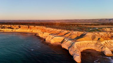 Blanche Point ve Maslin Sahili 'nin hava aracı görüntüsü Güney Avustralya Fleurieu Yarımadası' nda. Dramatik kumtaşı uçurumları, turkuaz okyanus dalgaları, altın plajlar ve canlı günbatımı renklerini gösteren bu kıyı manzarası nefes kesici bir manzara sunuyor.