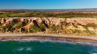 Blanche Point ve Maslin Sahili 'nin hava aracı görüntüsü Güney Avustralya Fleurieu Yarımadası' nda. Dramatik kumtaşı uçurumları, turkuaz okyanus dalgaları, altın plajlar ve canlı günbatımı renklerini gösteren bu kıyı manzarası nefes kesici bir manzara sunuyor.
