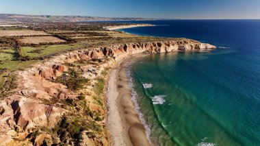 Blanche Point ve Maslin Sahili 'nin hava aracı görüntüsü Güney Avustralya Fleurieu Yarımadası' nda. Dramatik kumtaşı uçurumları, turkuaz okyanus dalgaları, altın plajlar ve canlı günbatımı renklerini gösteren bu kıyı manzarası nefes kesici bir manzara sunuyor.