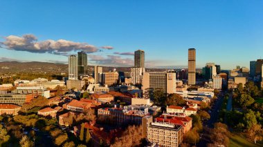 Adelaide CBD 'nin Güney Avustralya' daki hava batımı görüntüsü, şehrin modern gökdelenlerini, yüksek gökdelenleri ve yeşil parklarla çevrili Adelaide Üniversitesi kampüsünü gösteriyor. Görüntü, şehir manzarasını sıcak altın saatinde yakalıyor.