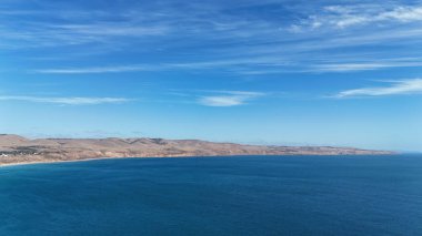 Bu drone görüntüsü Güney Avustralya 'daki Aldinga Sahili' nin büyüleyici güzelliğini yakalıyor. Kristal berrak sularını, beyaz kumlu sahil şeridini ve canlı sahil toplumunu gözler önüne seriyor. Sahil yolu, kumda park etmiş araçlar, ve yuvarlanan tepeler.