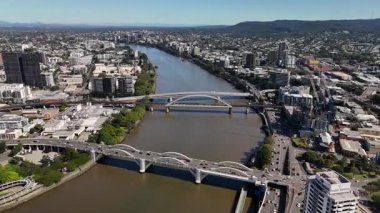 Queensland, Avustralya 'daki Brisbane CBD' nin 4K hava aracı görüntüleri modern şehir silueti, yüksek gökdelenler ve dolambaçlı Brisbane Nehri 'ni gösteriyor. Simgesel köprüleri, şehir altyapısını, South Bank parklarını ve canlı sahil kenarlarını yakalıyor.