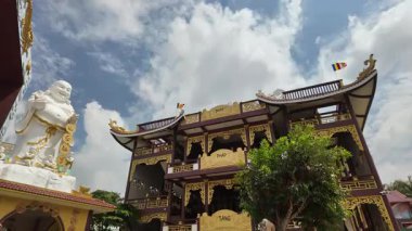 My Tho 'daki Lien Hoa Pagoda' da Tien Giang, Vietnam 'da çekilen Tien Hoa videoda zarif Avalokiteshvara Guanyin Buda heykelinin arka planda bulutlar sürükleniyor. Huzurlu bir tapınak bahçesine kurulmuş bu görüntü,