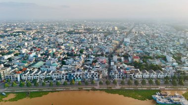 Bu çarpıcı 4K hava görüntüsü, Vietnam 'daki My Tho City' nin Mekong Deltası 'ndaki Tien Nehri boyunca yoğun bir yerleşim alanını çekiyor. Sahne, geleneksel ve modern mimari, ağaç sıralı caddeler ve kenetlenmiş kargoların uyumlu bir karışımını vurguluyor.