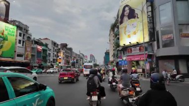 Bu çarpıcı 4K görüntülerde, yeşil trafik ışıkları altında motosiklet, araba ve sokak aktiviteleriyle gün batımında hareketli bir Saigon kavşağı görülüyor. Canlı şehir manzarası koloni mimarisi, modern dükkanlar ve hareketli sokak yaşamını harmanlıyor.