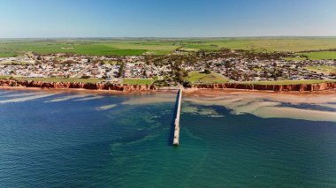 Güney Avustralya 'daki Yorke Yarımadası' nda yer alan Ardrossan, yüksek kızıl kıyı kayalıkları, tarihi iskelesi ve büyüleyici deniz kenti atmosferiyle ünlüdür. Bu 4K hava aracı engebeli kıyı şeridinin nefes kesici görüntülerini kaydediyor.