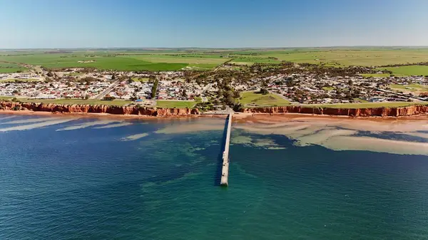 Güney Avustralya 'daki Yorke Yarımadası' nda yer alan Ardrossan, yüksek kızıl kıyı kayalıkları, tarihi iskelesi ve büyüleyici deniz kenti atmosferiyle ünlüdür. Bu 4K hava aracı engebeli kıyı şeridinin nefes kesici görüntülerini kaydediyor.