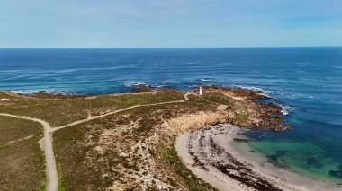 Bu görüntü, mavi okyanusun arka planına karşı engebeli bir sahil şeridinde duran tarihi Corny Point Deniz fenerini yakalar. 1882 'de inşa edilen deniz feneri, Spencer Körfezi boyunca gemilere yol gösteren simgesel bir deniz simgesi olmaya devam ediyor. Sahne gösteriyor ki
