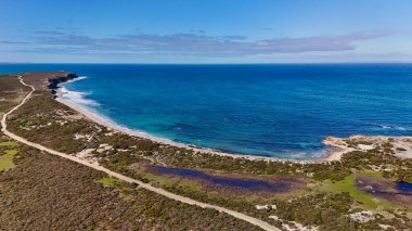 Güney Avustralya, Yorke Yarımadası, Innes Ulusal Parkı 'ndaki Stenhouse Bay Jetty' nin çarpıcı hava aracı görüntüsü. Görüntüler, engebeli sahil kayalıkları ve el değmemiş Güney Okyanusu tarafından çerçevelenmiş turkuaz sulara uzanan tarihi ahşap iskeleyi yakalıyor.