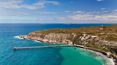 Güney Avustralya, Yorke Yarımadası, Innes Ulusal Parkı 'ndaki Stenhouse Bay Jetty' nin çarpıcı hava aracı görüntüsü. Görüntüler, engebeli sahil kayalıkları ve el değmemiş Güney Okyanusu tarafından çerçevelenmiş turkuaz sulara uzanan tarihi ahşap iskeleyi yakalıyor.