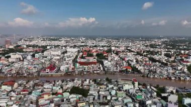 Mekong Delta, Vietnam 'daki My Tho City' nin 4K hava aracı görüntüsü. Geleneksel ve modern evlerin, renkli çatıların, balıkçı teknelerinin ve canlı nehir kenarındaki yaşamın karışımıyla Bao Dinh Kanalı boyunca nehir kenarındaki yerleşim alanları yer alıyor.