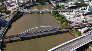 Queensland, Avustralya 'daki Brisbane CBD' nin 4K hava aracı görüntüleri modern şehir silueti, yüksek gökdelenler ve dolambaçlı Brisbane Nehri 'ni gösteriyor. Simgesel köprüleri, şehir altyapısını, South Bank parklarını ve canlı sahil kenarlarını yakalıyor.