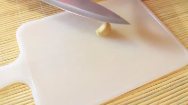 Bir adam tahtanın üzerinde sarımsak doğruyor