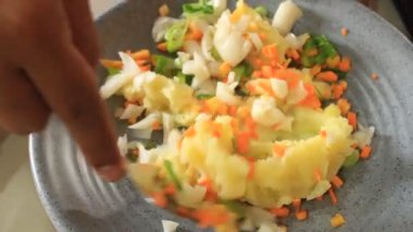 Patates hamurunu çeşitli sebzelerle karıştırmak. Bir insan patates hamuru karıştırır.