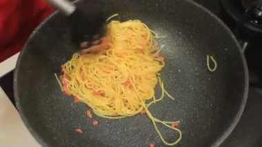 Birisi spagetti pişiriyor. Tavada erişte pişirmek.