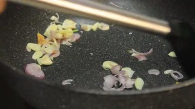 Tavadaki baharatları sote et. Birisi kızartma tavasında baharat kızartıyor.