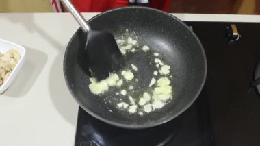 Bir kişi yüzünde sarımsak kızartmış. Sarımsak kızartma tavasında kızarır.