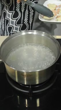 Birisi haşlanmış un sosisi pişiriyor. İşlenmiş yiyecekler kaynar.