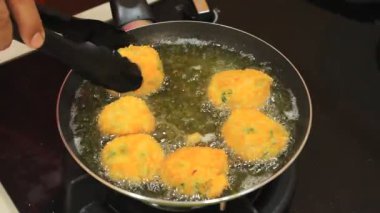 Kızarmış yuvarlak tabak. Birisi yuvarlak şekilli yemek kızartıyor.