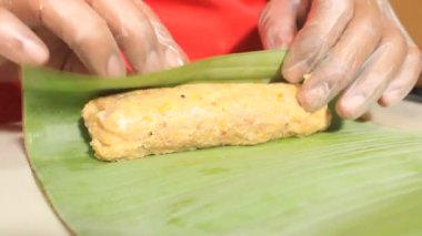 Hamuru muz yapraklarına sar. Birisi muz yapraklarıyla yemek yapıyor.