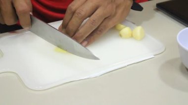 Biri sarımsak doğruyor. Sarımsağı bıçakla doğra.