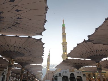 El-Mescid an-Nabawi 'nin Minareleri ve Dev Şemsiyeleri Medine, Suudi Arabistan' da Gündoğumunda
