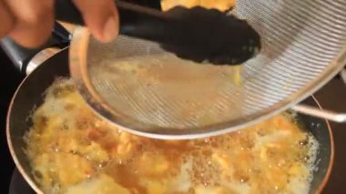 Kızarmış tavuk pişti. Birisi kızarmış tavuğu süzüyor.