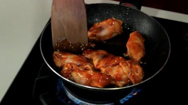 Bir şef baharatlı tavuk pişirir.