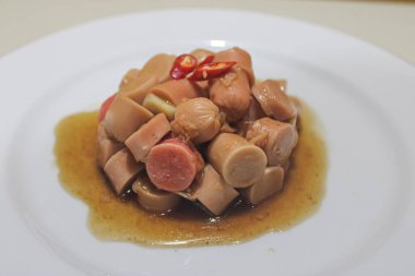 Beyaz tabakta acı dilimli sahanda sosis.