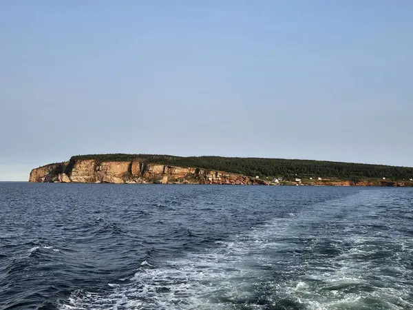 Hareket halindeki teknenin panoramik kıyı manzarası altın kireçtaşı uçurumlarını ve berrak gökyüzü altında sakin mavi suları gösteriyor. Geniş deniz perspektifi deniz seviyesinden geniş bir kıyı şeridi yakalıyor. Mükemmel sahil gezisi ve gezi fotoğrafçılığı içeriği.