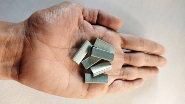 Beyaz ve gümüş metal küpleri tutan bir elin yakın plan çekimi.