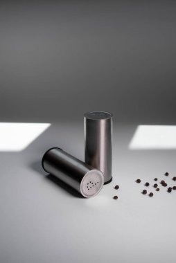 Metal biber karıştırıcı ve tuzluk, güneşten gelen ışıkla beyaz arka planda biber.