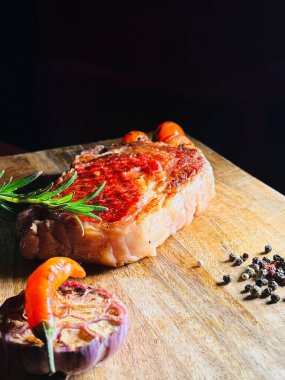 Sarımsak ve biberli sulu biftek. Köy tahtasında servis edilen sulu, sulu bir biftek. Taze sarımsak karanfili ve karabiberle süslenmiş.. 