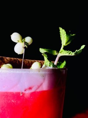 Cocktail close-up, beautifully decorated. Cold drink on a black background. A close-up view of a refreshing cocktail, elegantly garnished with fresh ingredients and served chilled.