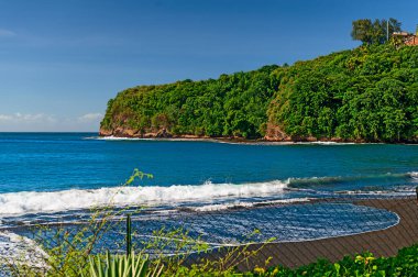 Tahiti 'deki sahil şeridi bilinmeyen bir tatil köyünün önünde siyah bir kumsal gösteriyor.