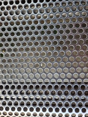Delinmiş paslanmaz çelik tezgah dokusu, simetrik deliklerle modern endüstriyel tasarımı ve doğal ışık altında yansıtıcı metalik yüzeyi sergiliyor..