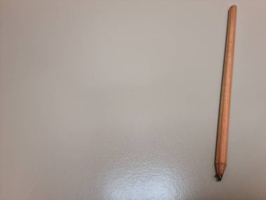 Modern ya da geleneksel çalışma alanlarında basitliği, yaratıcılığı ve zamansız yazma araçlarını temsil eden, temiz bir yüzeyde duran klasik bir tahta kalem..