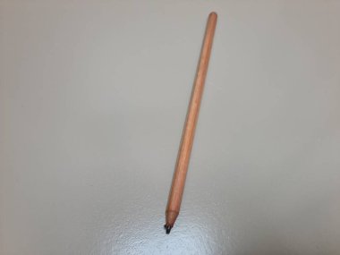 Modern ya da geleneksel çalışma alanlarında basitliği, yaratıcılığı ve zamansız yazma araçlarını temsil eden, temiz bir yüzeyde duran klasik bir tahta kalem..