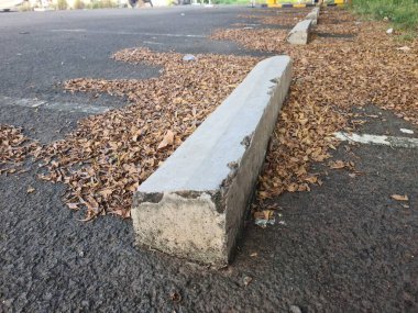 Kuru yapraklarla dolu bir yere park etmiş bir araba tamponu kentsel bir ortamda sessiz ve sonbahar havasını çağrıştırıyor..