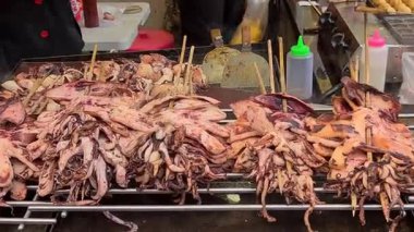 Cakarta, Endonezya - 29 Haziran 2025: Açık ateşte ızgara kalamar satay, dumanlı, sulu deniz ürünleri şişleri pişiriliyor, Asya 'daki gece pazarlarında popüler..